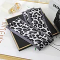 Detailed macro view of a leopard print skinny scarf styled on a luxury display board - L040-08-01 Large Leopard Print - White