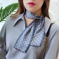 Close-up of a blue silk scarf with white polka dots tied around the model's neck. - Mist Blue Polka Dot / 10*100cm