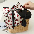 Close-up of a French retro silk scarf with red heart patterns tied to a basket bag - Red Heart Reflects White / 10*100cm