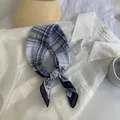 Vista dettagliata di un foulard di seta a quadri blu e gialli annodato sopra un colletto bianco. - Lm58-navy phantom line grid / 58*58cm