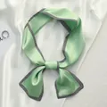 Detail view of light green silk scarf with black white striped border tied in bow. - Mint Twill / 10*100cm