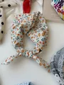 Close-up detail of a knotted cotton linen neckerchief featuring a delicate orange floral print - 21 Wild Fruits
