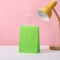 Close-up of a vibrant light green kraft paper gift bag with twisted white handles. - Fruit Green