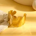 Detail van een gouden roestvrijstalen manchetarmband met geometrisch bladmotief - Veerblad Verticale Streep Stijl (S851) / Goud
