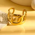 Close-up van een dikke gouden geometrische holle manchetarmband van roestvrij staal - Minimalistische Industriële Holle Geometrische Stijl (S849) / Goud