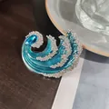 Primo piano di una spilla di lusso a forma di onda con smalto blu e strass luccicanti - Verde