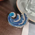 Dettaglio macro spilla onda blu con strass brillanti e gemma azzurra a goccia fine - Blu