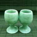 Macro detail of two handcrafted green jade goblets on a traditional bamboo mat background. - Guizhou Cui Style