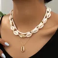 Detalle de un collar de capas estilo océano con conchas y perlas en una modelo - Estilo en Capas Concha (01)