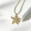Collana con ciondolo a forma di stella marina dorata con cordino intrecciato bianco. - 14k / Oro