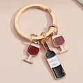 Elegant gold keychain with red wine glass and bottle enamel charms on beige background - Golden Wine Bottle & Cup (E3939)