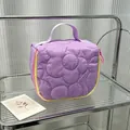 Detail view of a quilted purple floral cosmetic bag with a handle on a glass shelf. - 14.5*8.5*14.5cm / Purple