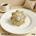 Elegant gold starburst brooch featuring a central pearl and shiny rhinestone accents - KC Gold Radiant Firework
