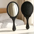 Vintage black handheld makeup mirror with embossed pattern and decorative scalloped edge. - Oval / 11.5x25cm / Black