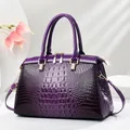 Elegante paarse laks handtas met krokodillenreliëf en goudkleurige hardware. - L33 B14 H21 / Paars
