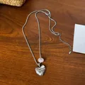 Minimalistische zilveren hart hanger ketting met gravure en roze kraal op houten tafel. - Roze Kraal Hart Hanger / Zilver-Kattenoog-Hart