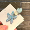 Makroansicht der Haarspange im Ozean-Stil mit glitzerndem blauem Seestern und Herz auf Karte - Eis Herz Seestern / Blau