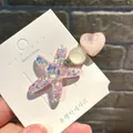 Detailansicht einer rosa glitzernden Seestern- und Herz-Haarklammer auf einer Karte. - Eis Herz Seestern / Rosa