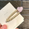 Eleganter glitzernder rosa Herz-Haarclip mit weißen Perlen auf goldfarbenem Metallsockel - Wassertropfen Eis Herz / Lila