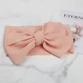 Close-up detail of soft peach baby headband featuring waffle texture and large bow design - Off White