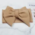 Close-up detail of the textured tan corn grain fabric and the large decorative bow design - Khaki