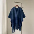 Detailed view of a thick blue houndstooth shawl poncho with tassels hanging on a rack - Blue / 170x110cm（750g）