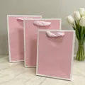 Elegant pink paper gift bags with white borders and soft ribbon handles in various sizes. - (Vertical) 16L*8W*22H / White Edges on Foundation