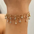 Close-up detail of golden chain bracelet with dangling zircon stones and circular charms. - Geometric Ring Tassel Bracelet (A-930) / KC Gold