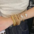 Set of four gold-finish metal bracelets featuring irregular pearls and coiled designs. - 27# Bracelet - Gold (three-piece Set)