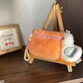 Plush pelican storage bag in vibrant orange and white displayed on wooden easel - B60 Pelicans Orange Mid-pack