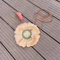 Close-up detail of a cute tan flower-shaped children's bag on a rustic wooden platform - Khaki Flowers