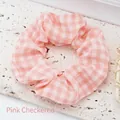 Detailed view of a pink and white checkered fabric scrunchie hair tie. - Pink Plaid