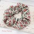 Close-up view of a pink floral print cloth scrunchie on a white textured stone base. - Pink Floral
