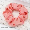 Close-up detail of a soft pink floral print fabric scrunchie resting on white stone - Pink sunflower