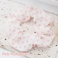 Close-up of a stylish white fabric scrunchie with cute pink polka dot patterns. - Pink Polka Dot