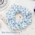 Detailed macro view of a white fabric scrunchie with blue floral print on stone base - Blue Flowers 1