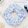 Close-up of a blue floral fabric scrunchie with delicate flower patterns on white base. - 5 Blue Flowers