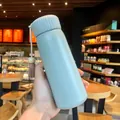 Close-up of a light blue insulated water bottle with a decorative tassel in a cafe - Large / 400ml Size / Green