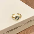 Macro detail of a vintage gold floral open ring with gradient blue enamel and a white pearl. - Style 1 Blue Floral