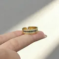 Close-up of a vintage-style gold ring featuring sapphire and diamond accents on a finger - Adjustable Open / Gold (Blue Rhinestone)