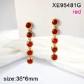 Close-up detail of elegant gold-toned long drop earrings with five round red faceted stones - Red