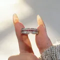Close-up of a vintage-style ruby and diamond row ring being held in elegant sunlight - Adjustable Open / Platinum Plated With Red Zirconia