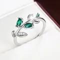 Macro detail of silver branch ring featuring marquise-cut emerald green stone leaves - Silver & Green