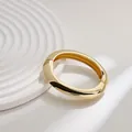 Brazalete dorado irregular con bisagra de resorte sobre base minimalista ondulada - Brazalete Redondo Curvo (As0062)