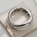 Brazalete irregular de aleación plateada con muelle sobre una placa de piedra pulida. - Brazalete de Onda Curva Lisa (As0055)