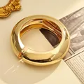 Elegante brazalete de resorte dorado grueso con un acabado metálico pulido de alto brillo. - Estilo Circular de Borde Ancho (As0133)