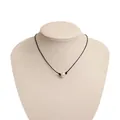 Vista detallada de un collar de perlas minimalista con cordón negro y soporte beige. - Perla Artificial Única (ZRX0165)