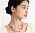 Elegant model wearing bohemian multi-layer gravel necklace and earring set in amber - Lotus Red