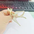 Handheld view of a delicate white enamel swallow brooch with sparkling rhinestones - Xz14-006 White Swallow