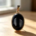 Elegant oval black agate gemstone pendant with golden bezel setting on a wooden surface - Obsidian Pendant / 1 Piece/Pack / Black